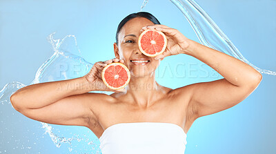 Buy stock photo Beauty, cleaning and grapefruit by woman in studio for health, wellness and cosmetic treatment against blue background. Fruit, skin and model relax with detox, diet and water skincare splash product