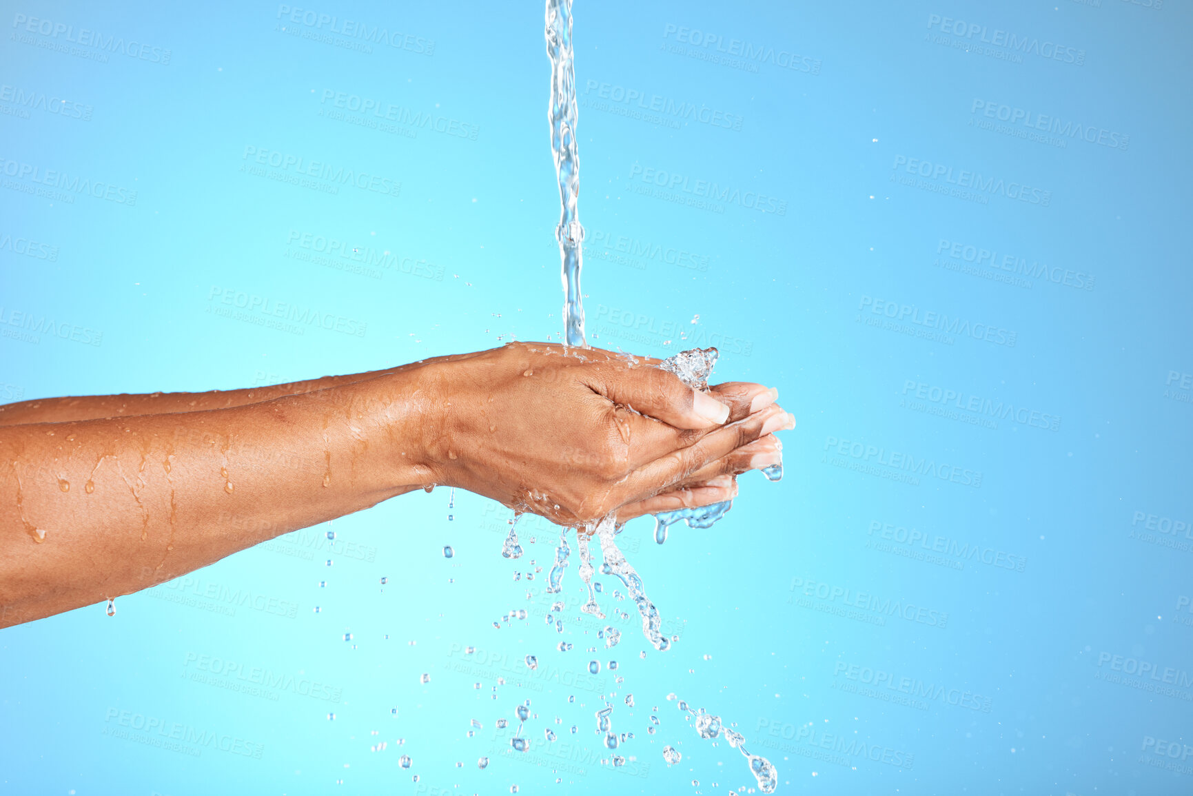 Buy stock photo Hands, water and woman in studio for cleaning, washing hands and safety from bacteria against a blue background. Hand, splash and model washing for skincare, hygiene and germ prevention with mockup