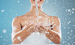 Water, woman and hygiene doing clean, with smile and clear skin being happy, confident and bare with blue studio background. Female, bare and with towel with splash fluid, pride or cosmetics for body