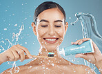 Woman, brushing teeth and with smile, happy and water splash for wellness, dental care and with blue studio background. Oral hygiene, young female and girl being confident, toothpaste and tooth brush