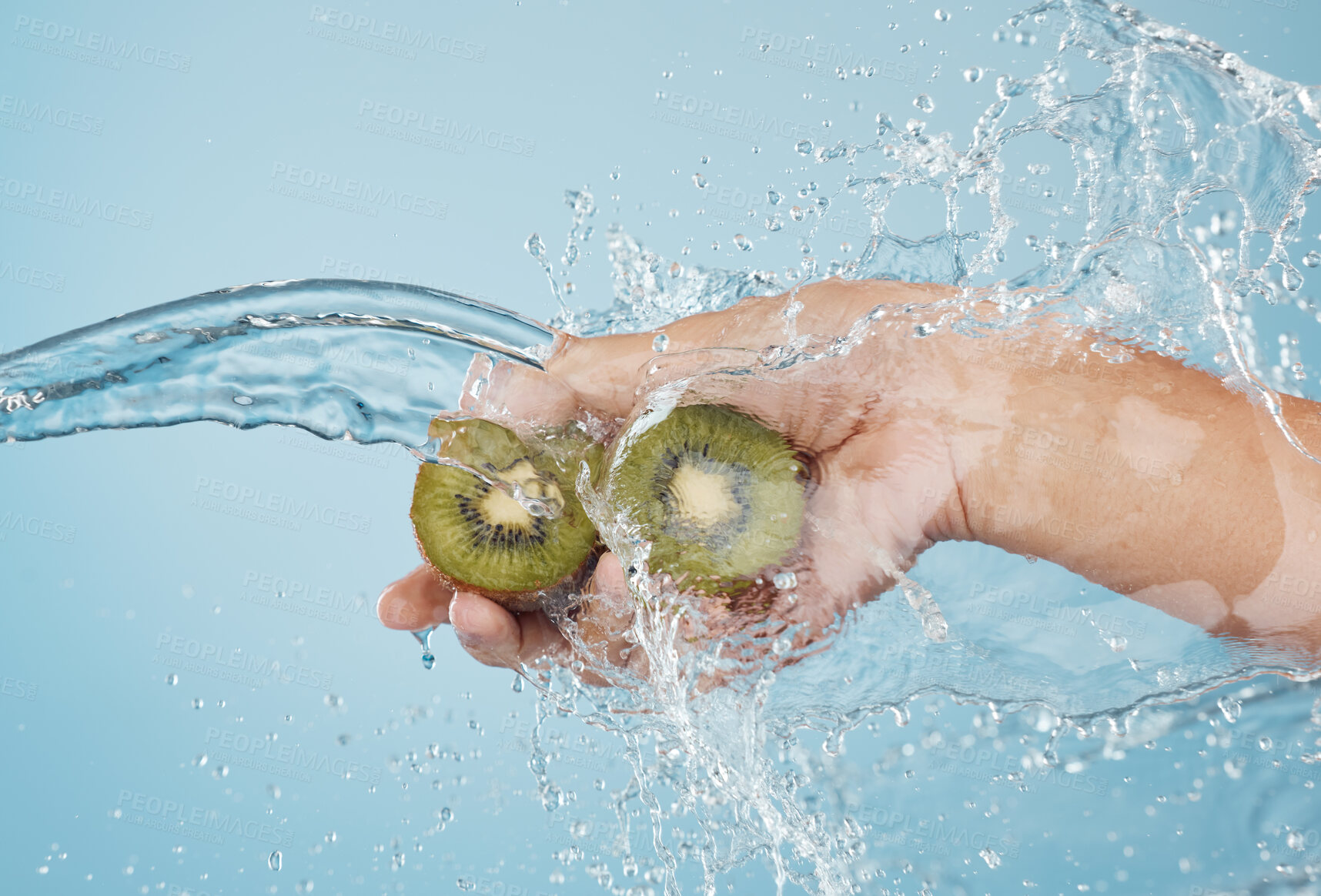 Buy stock photo Hands, beauty and kiwi in a studio with splash for skincare, shower and organic treatment against a blue background. Hand, water and fruit with woman wellness model grooming, hygiene and cleaning