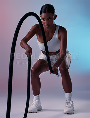 Buy stock photo Girl, fitness and rope training exercise for cardio, muscle and endurance practice with color studio background. Focus, health and power of Indian woman training with gym wellness workout gear.


