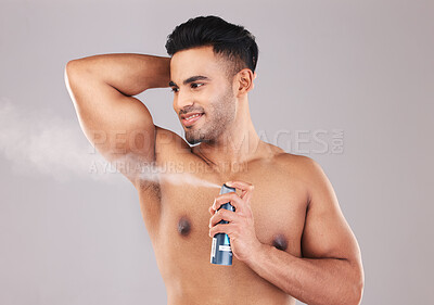 Buy stock photo Deodorant, armpit and man spraying in studio for hygiene, wellness and self care. Spray, clean and young model from Colombia with fragrance with a fresh scent for grooming isolated by gray background