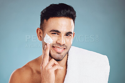 Buy stock photo Cream, skincare and portrait of the face of a man with moisturizer after a shower against a blue mockup studio background. Sunscreen, wellness and smile of a young model with facial creme for skin