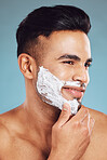 Shaving, cream and face of a man cleaning a beard for skincare, wellness and beauty against a blue mockup studio background. Thinking, happy and model with idea for facial hair, creme and smile