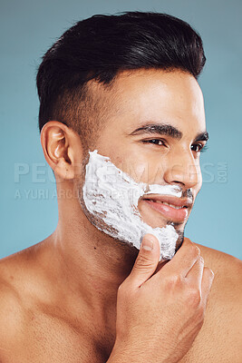 Buy stock photo Shaving, cream and face of a man cleaning a beard for skincare, wellness and beauty against a blue mockup studio background. Thinking, happy and model with idea for facial hair, creme and smile