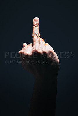 Buy stock photo Middle finger, rude and disrespect with the hand of a man in studio on a dark background with light highlight. Angry, sign and gesture with a male showing hatred with an obscene or aggressive symbol
