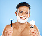 Man, razor and shaving cream for skincare, grooming or facial treatment against a blue studio background. Portrait of a happy male with smile holding cosmetics for shave, beauty or hygiene on mockup