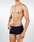 Body, fitness and health with a topless man model posing in underwear in studio on a gray background for wellness. Skin, healthy and natural with a muscular male athlete inside to promote lifestyle