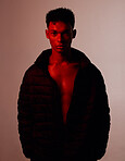 Portrait, fashion and style with a man model in studio on a wall background with red light for contemporary clothes. Beauty, confidence and edgy with a handsome young male posing for trendy clothing