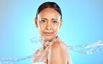 Skincare, water splash and woman in studio for wellness, beauty and skin, water and product on blue background. Cleaning, beauty splash and portrait of girl model shower, relax and splash aesthetic