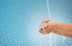 Water splash, cleaning hands and hygiene on blue background, advertising or product placement space. Health, skincare and safety from germs or bacteria, man washing hand in water in studio background