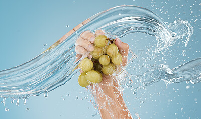 Buy stock photo Hands with grapes, water splash and studio blue background of fruits sustainability, healthy lifestyle and juice detox, nutrition and vitamins. Bunch of clean, vegan and diet green grapes in wet palm