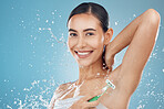 Studio, portrait and woman shaving armpit with a razor blade for hair removal, hygiene and body wellness. Smile, blue background and happy young girl shaves underarms for healthy clean skincare 