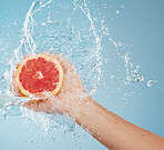 Hands with grapefruit, water splash and studio blue background of summer fruit, healthy lifestyle and detox, nutrition and vitamin c. Clean, vegan and citrus juice diet for skincare, beauty and body