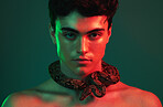 Snake, beauty and man in studio with green mock up with cosmetics, skincare and lights aesthetic for creative, art and animal print. Neon creativity, natural and nature pet fearless model on mockup