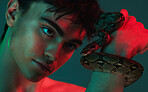 Beauty, fashion and portrait of man with snake in neon studio shoot with danger and creative art style. Skincare, color and lights, healthy male model with seductive and sexy look on green background