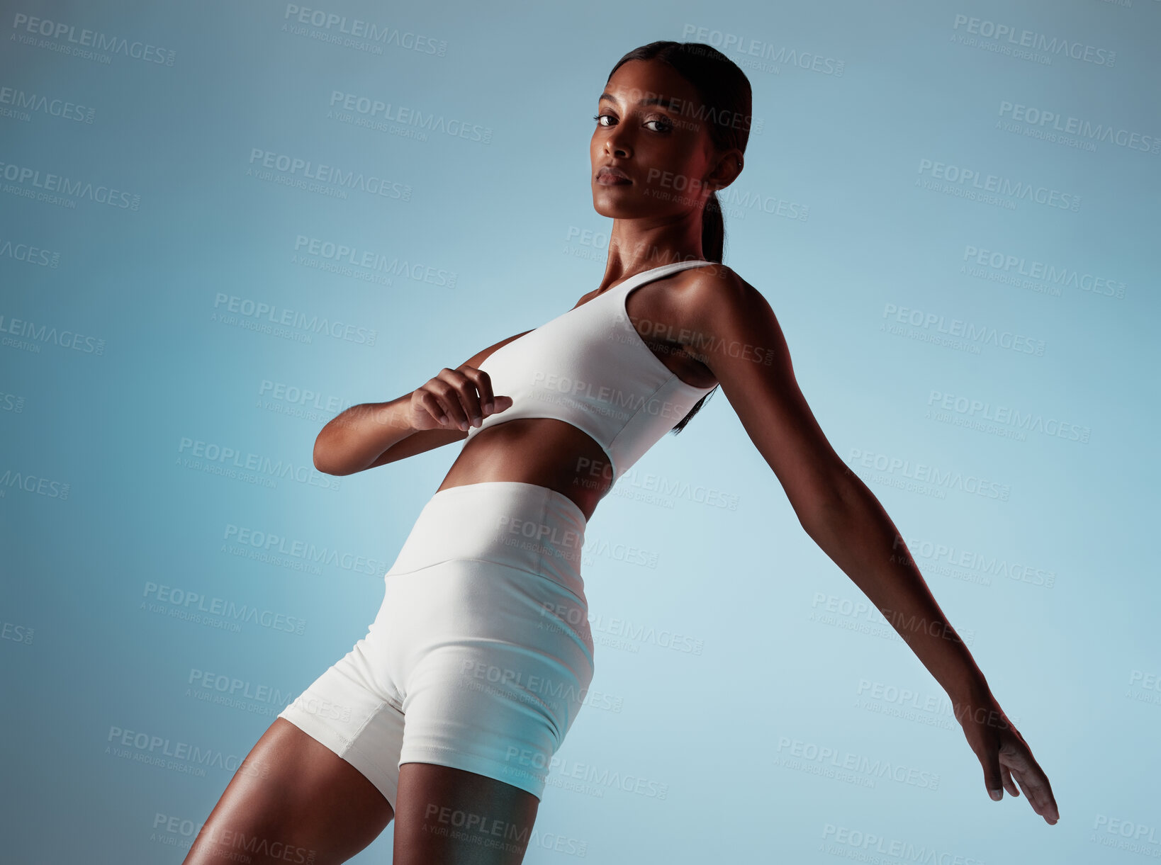 Buy stock photo Fitness, body and stretching woman in studio portrait with workout clothes on blue mock up for marketing or advertising space. Young black woman or fashion model dancing and training with mockup