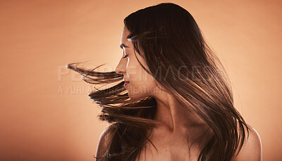 Buy stock photo Hair care, beauty and woman with care for body against a brown mockup studio background. Cosmetic, content and young girl model flipping her perfect, soft and healthy hair with mock up space