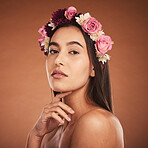 Flower, crown and woman with beauty, makeup and portrait against a brown studio background. Spring, cosmetics and face of a young model with flowers for summer, harmony and accessory in hair