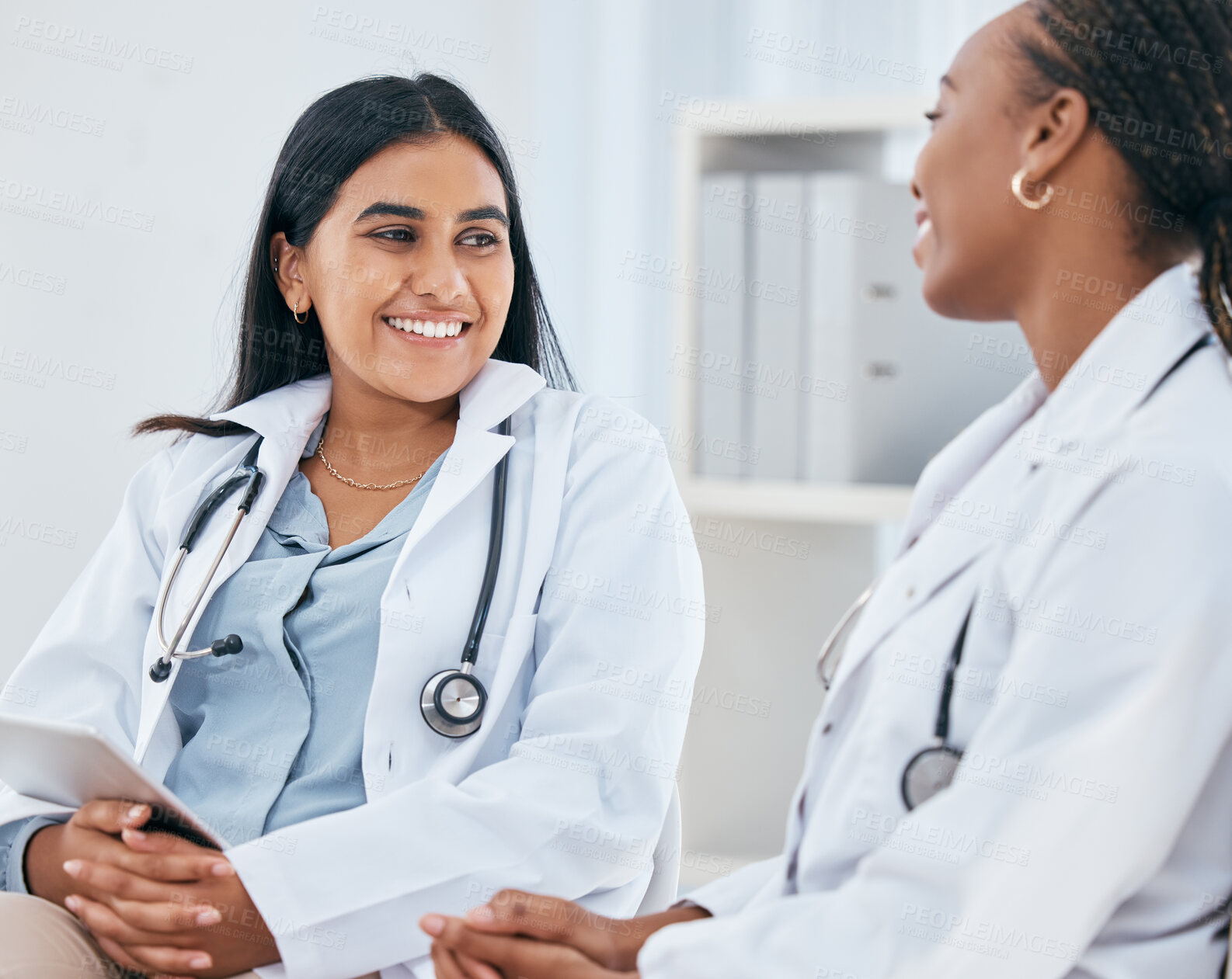 Buy stock photo Diversity, healthcare and doctors talking in hospital, having casual conversation, discussion and chatting. Medical workers, friends and Indian woman with black woman chat, talk and laugh in clinic