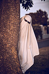 ghost costume, halloween and sunglasses in nature park outdoors. Funny horror dress up, spooky holiday celebration and creative scary mystery spirit design or hiding ghoul with glasses for carnival 