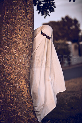 Buy stock photo ghost costume, halloween and sunglasses in nature park outdoors. Funny horror dress up, spooky holiday celebration and creative scary mystery spirit design or hiding ghoul with glasses for carnival 