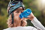 Water bottle, drink and woman in mountain bike travel, journey or adventure in nature forest for wellness, fitness or sports. Cycling sports girl in safety helmet gear drinking water in the woods