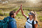 Couple, high five and hiking with motivation, goal and celebration for fitness target in nature with backpack. Man, woman and happy for partnership, excited or support while trekking together outdoor