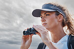 Woman, binoculars and hiking in nature, travel or outdoors vacation, holiday or trip in Canada. Freedom, cloudy sky and female on adventure, sightseeing or trekking and looking with field glasses.