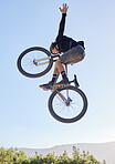 Bike jump, man and sport outdoor with biker and fitness, adrenaline and dangerous stunt with blue sky and sunshine. Freedom, extreme sports and young male on mountain bike, cyclist in nature.