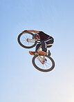 Mountain bike, speed and sports with a man jumping in the air during a race outdoor against the sky from a below. Blue sky, energy and bicycle with a professional male biker or athlete in action