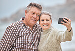 Phone, selfie and beach with a senior couple taking a photograph while on holiday or vacation travel together. Mobile, summer and retirement with a man and woman posing for a picture at the coast
