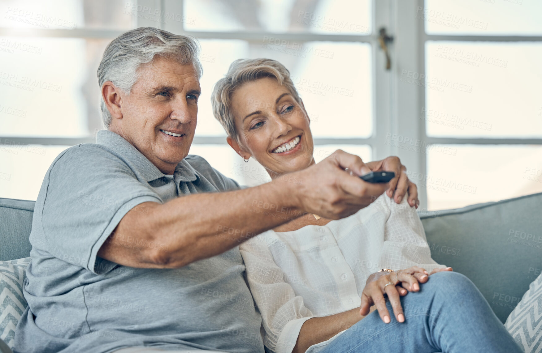 Buy stock photo Senior couple, smile and hug watching TV for entertainment on living room sofa with remote at home. Happy elderly man and woman relaxing on couch streaming movies, shows or media at the house
