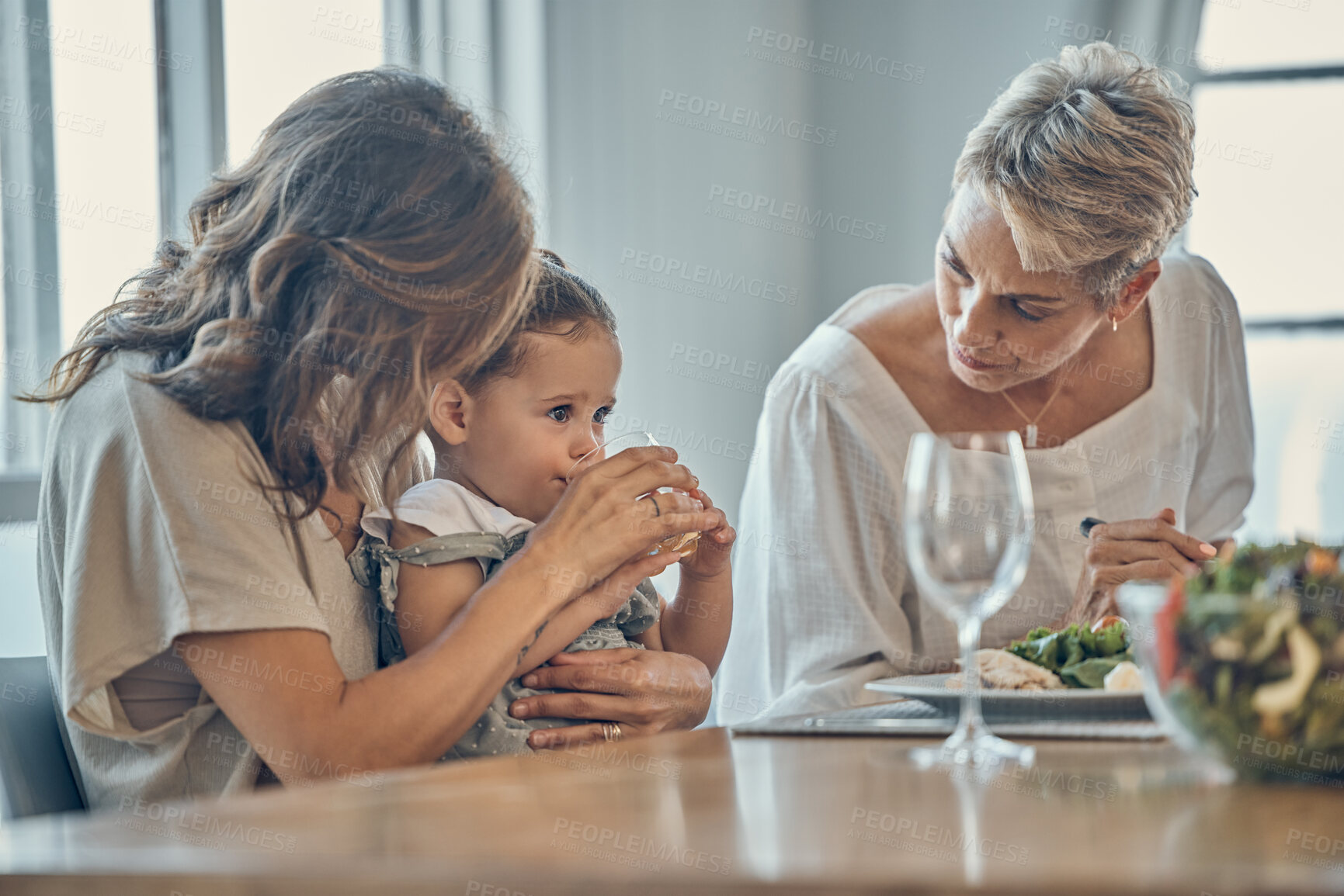 Buy stock photo Family, children and food with a mother, grandmother and girl drinking juice while eating together. Kids, love and lunch with a woman, daughter and grandparent enjoying a meal while bonding at home