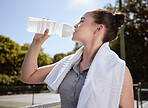 Fitness, woman with water bottle and hydrate after exercise workout, towel and drinking outdoor. Sport, healthy and active with break from training, hydration and health motivation with wellness.