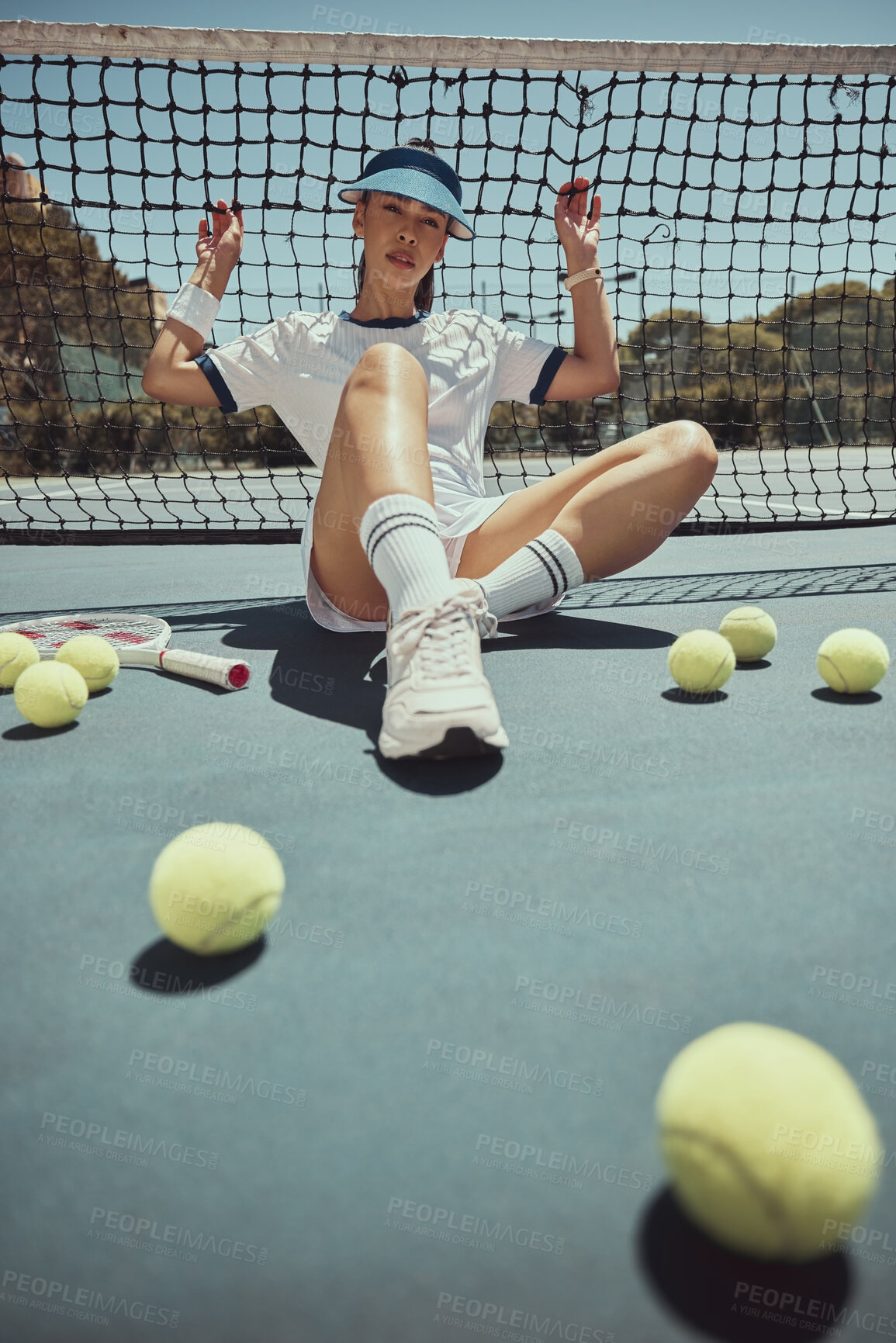 Buy stock photo Relax, portrait and tennis woman at net on exercise, fitness and court break at sports ground. Training, workout and cardio of professional athlete club girl resting on floor with tennis balls.
