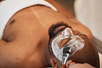 Black man spa, beauty skincare mask and lying relax for exfoliation on salon bed for cosmetic treatment. Man skin wellness, luxury facial cosmetics and healthy rest at resort for face moisturiser
