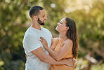 Happy, love and couple hug in a park, bond and talking and quality time against a nature, tree and bokeh background. Happy, smile and woman with man enjoying trust, support and relationship in forest