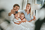 Morning, bed and happy family take a selfie with a smile enjoying quality time, bonding and relaxing at home. Pictures, mother and father with young children, kids or siblings in the house bedroom