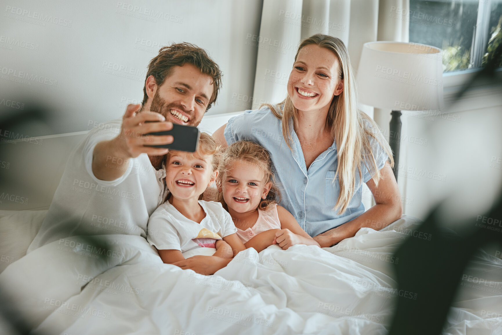 Buy stock photo Morning, bed and happy family take a selfie with a smile enjoying quality time, bonding and relaxing at home. Pictures, mother and father with young children, kids or siblings in the house bedroom