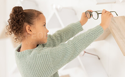 Buy stock photo Shopping, child and glasses vision choice for eye care at professional store with concentration. Independent, decision and young girl choosing eyeglasses frames and lens at mall shop with focus.