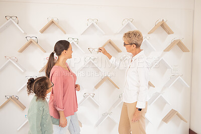 Buy stock photo Eye care, mother and child shopping for glasses at the optometrist store shelves with an optician for healthy vision. Customer, mom and young kid searching for frames at a shelf with an eye doctor 