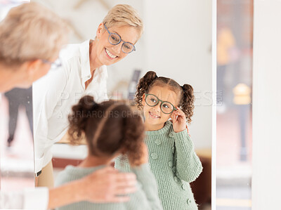 Buy stock photo Glasses, vision and children with a girl and woman optician looking in a mirror during an appointment or checkup. Eyewear, optometry and frame with a child customer shopping for prescription lenses