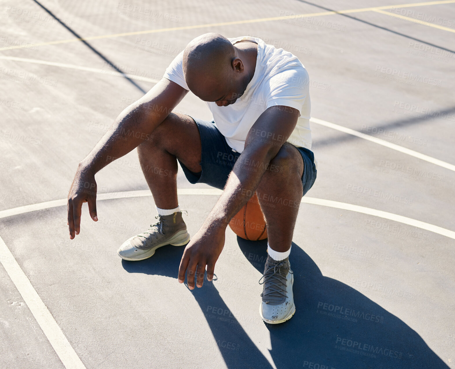 Buy stock photo Basketball court, tired and black man sitting on a basketball resting or relaxing on a fitness training or workout break. Loser, wellness and African sports athlete with fatigue in an exercise game