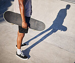 Skateboarding, sport and man holding a board for fun, riding and playing at a park. Legs, shadow and cool skater or skateboarder skating with a skateboard for sports and style in the urban city
