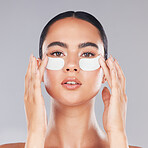 Face, skincare and woman with eye patches on a gray studio background. Portrait, beauty and model from Canada with facial collagen pads or dermatology product for anti aging, hydration or wellness.