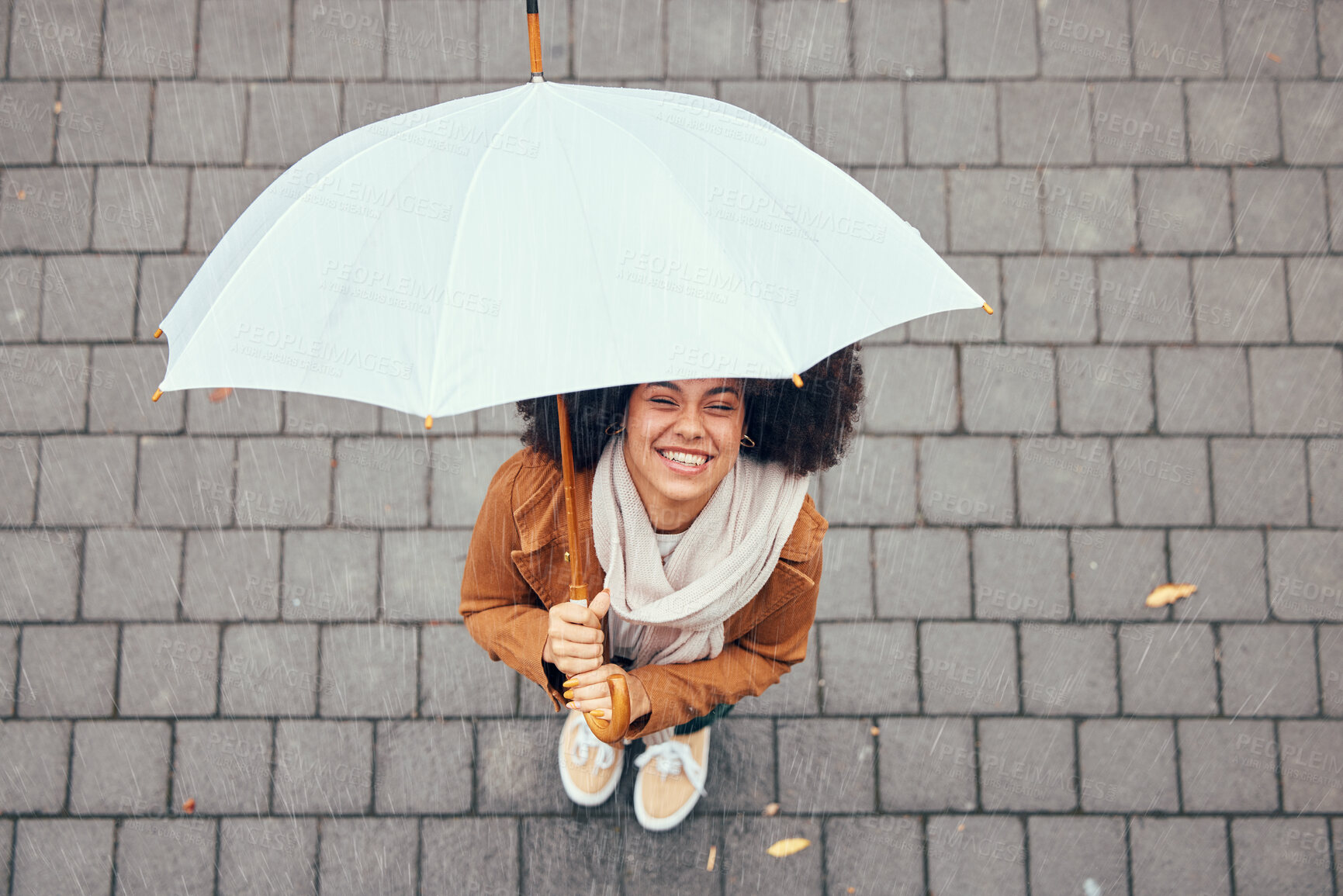 Buy stock photo Happy, relax and girl with rain umbrella enjoying outdoor, urban and winter weather with excited smile. Happiness, peace and wellness of black woman with afro standing in rainy city top view.

