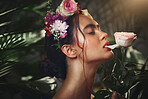 Beauty, nature and flowers with a model woman biting a rose in studio on a natural forest background. Skincare, wellness and luxury with an attractive young female posing in a rainforest jungle