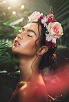 Face, beauty and flowers with a model woman in studio on a natural forest background for wellness or skincare. Nature, luxury and cosmetics with an attractive young female in a rainforest or jungle